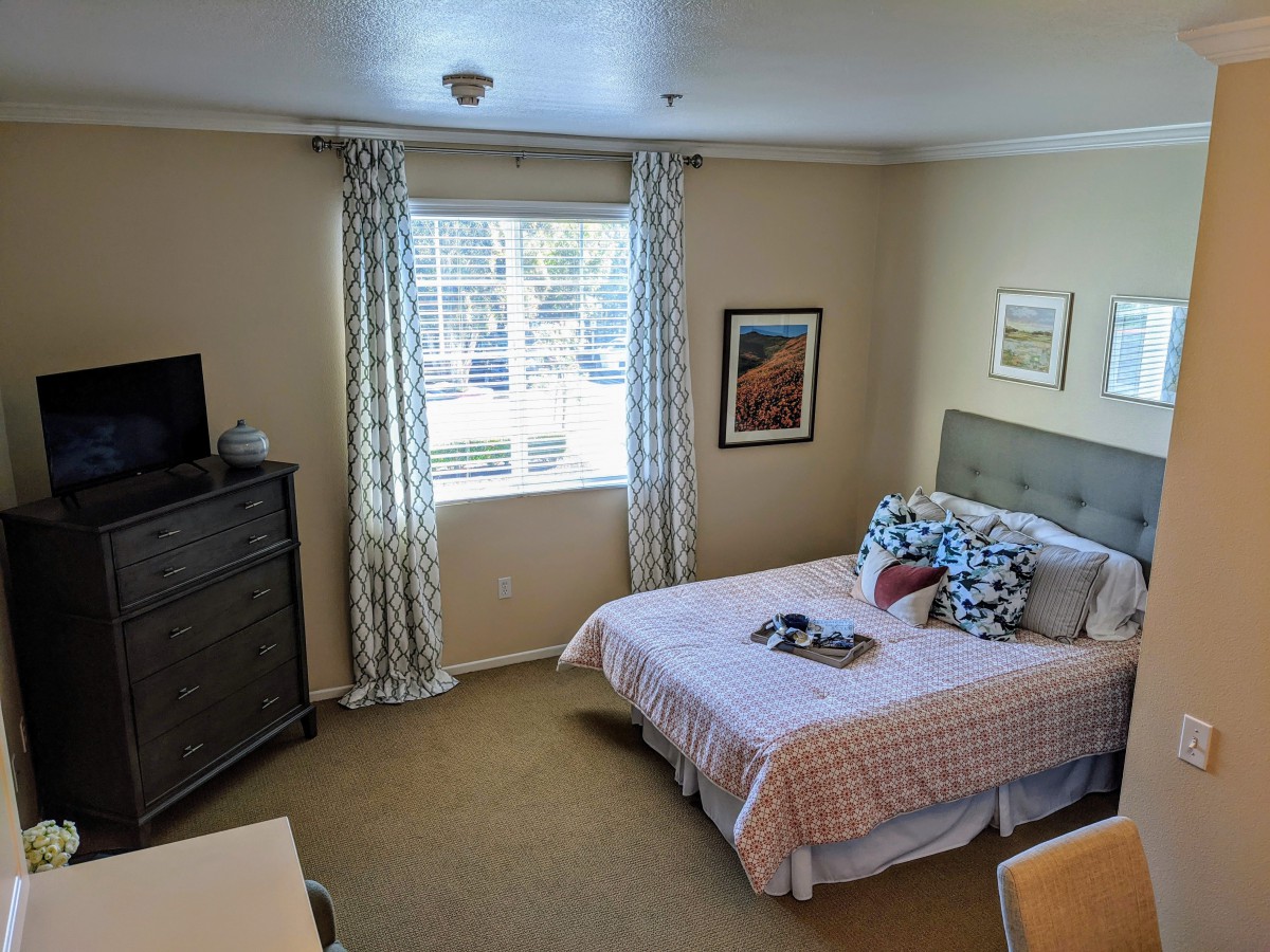 A neatly decorated bedroom with a bed, dresser, and artwork on the walls.