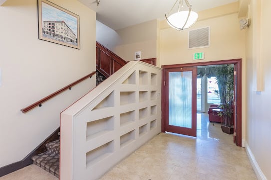 A well-lit lobby area featuring a staircase, built-in shelves, and an entrance door.