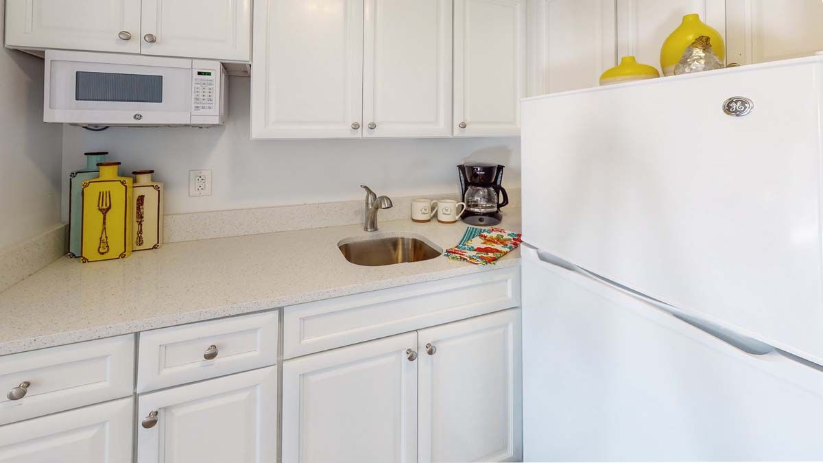 A clean and minimalistic kitchen with white cabinets and a coffee maker on the countertop.