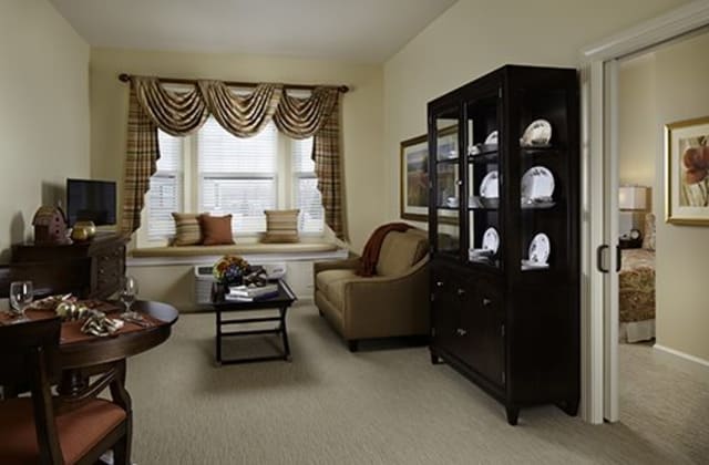 A cozy living room with elegant curtains, a comfortable sofa, and a stylish cabinet displaying decorative items.