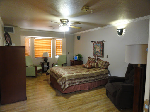 A cozy and well-furnished bedroom featuring a comfortable bed, chairs, and natural light from the windows.