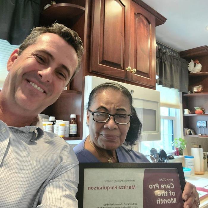 Two people taking a selfie in a kitchen, one holding a certificate.