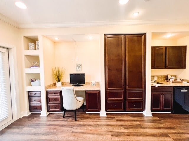 A neatly organized home office with a wooden desk, chair, computer, and ample storage space.