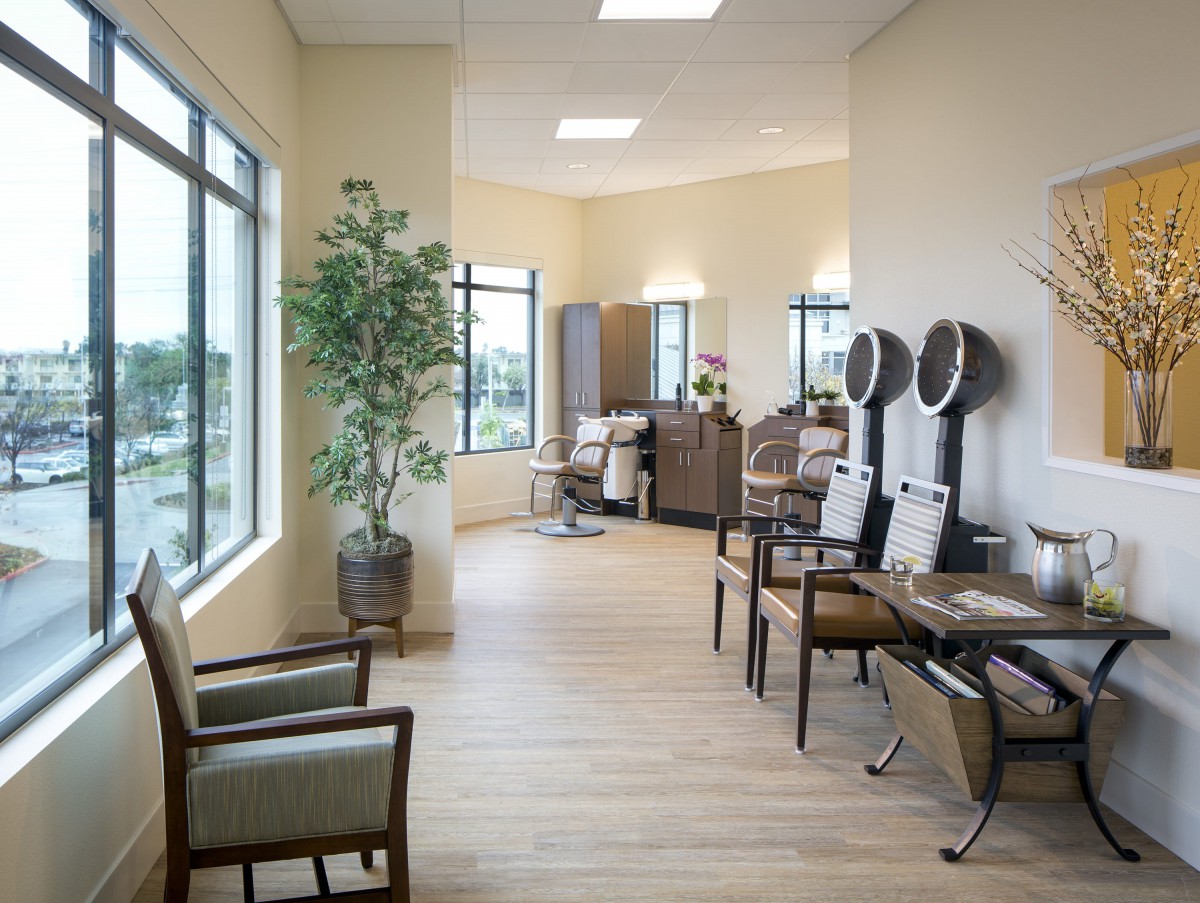 A modern salon interior with seating, mirrors, and hair drying stations.