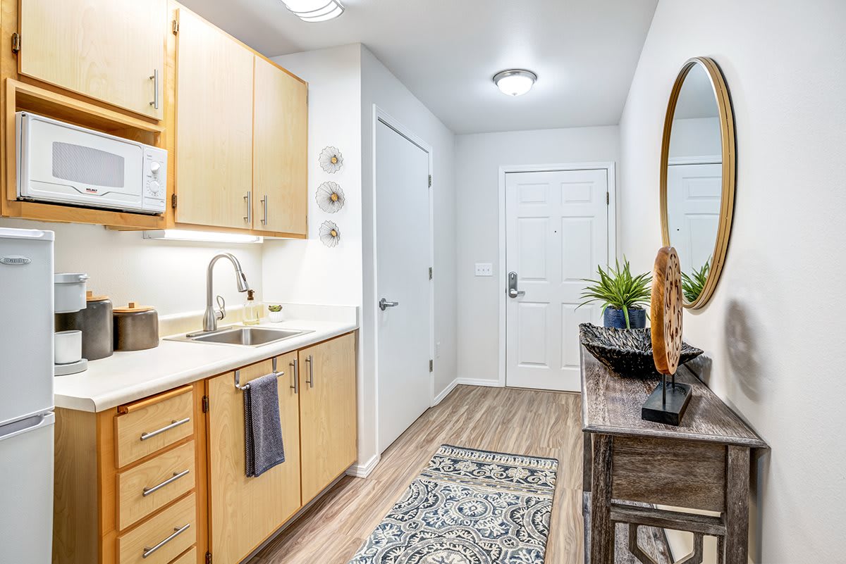 A modern apartment kitchen with light wood cabinets and tasteful decor.
