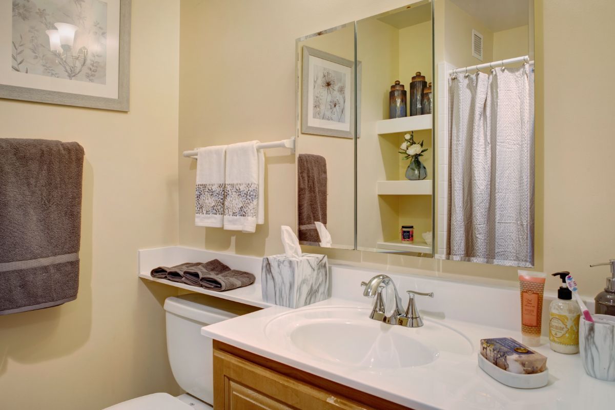 A neatly organized bathroom with a mirror, sink, and decorative elements.