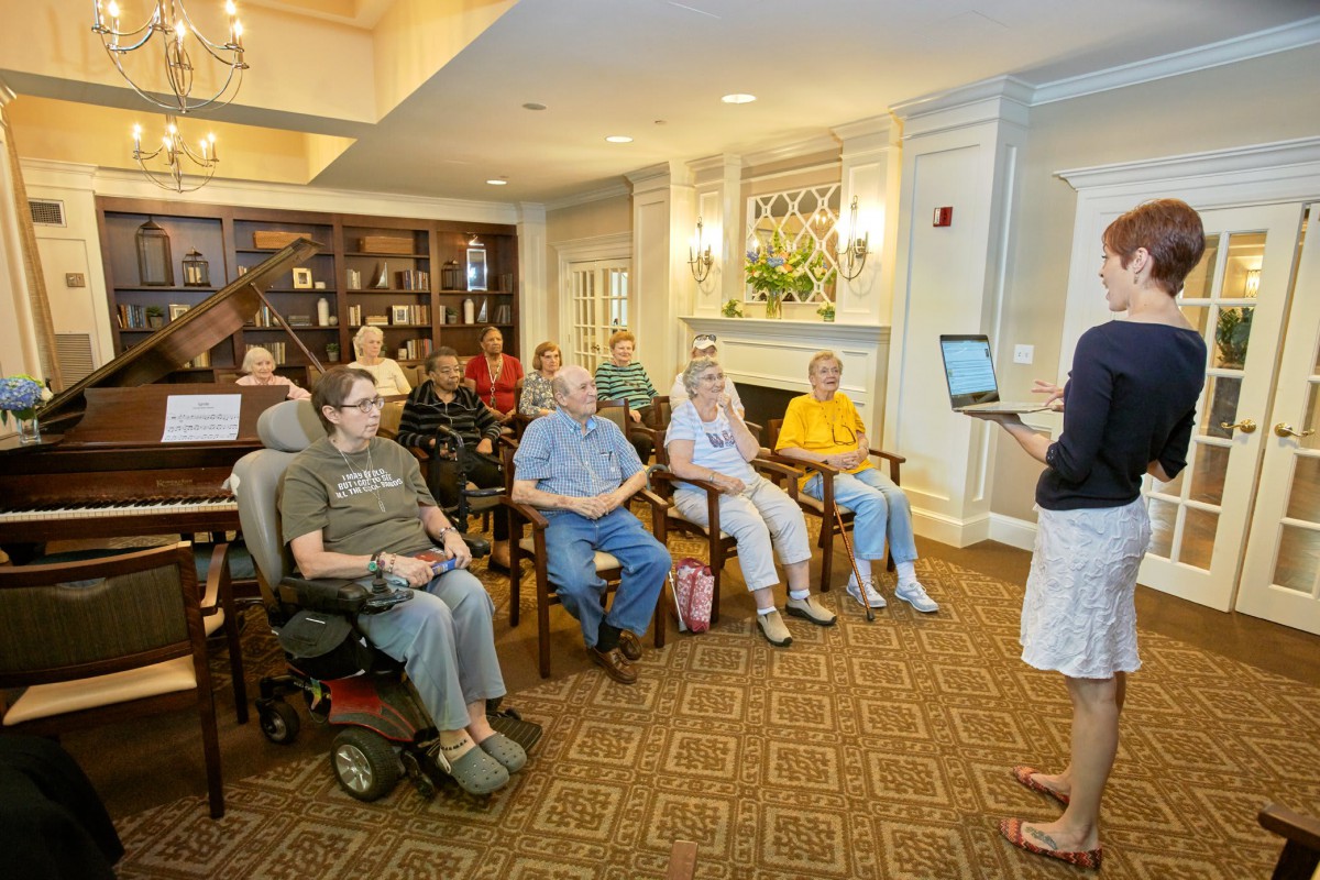 A group of senior citizens attentively listening to a presentation indoors.