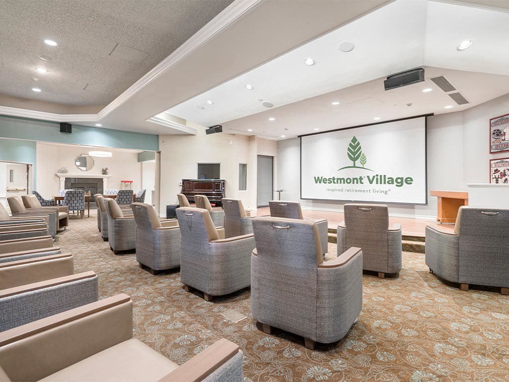 A modern theater room with comfortable armchairs facing a large screen.