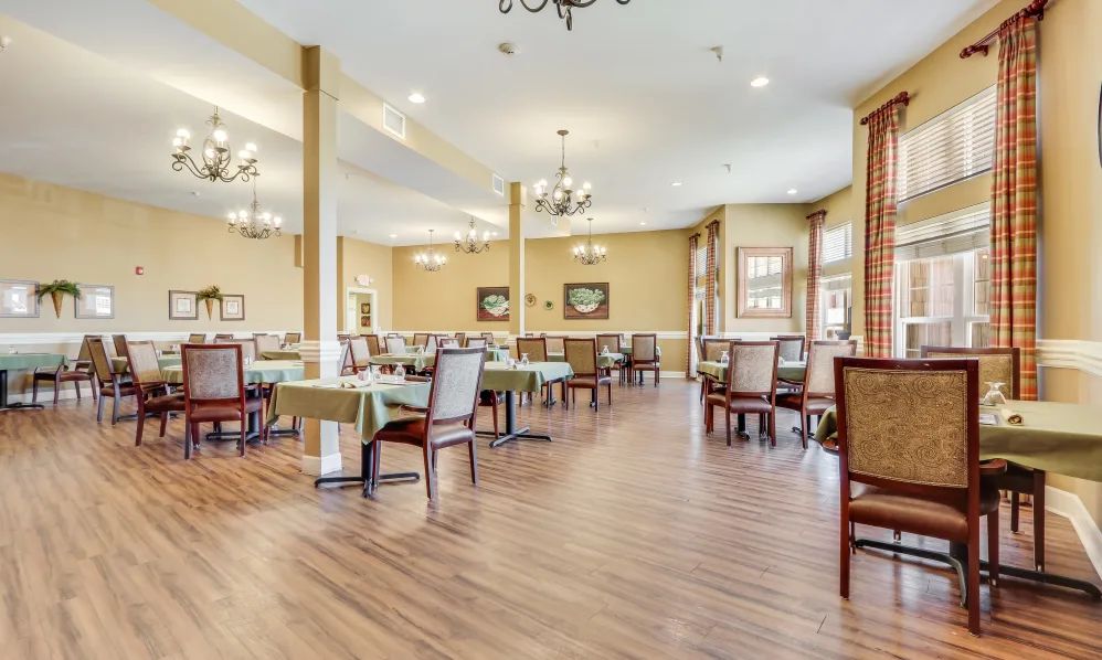 An elegant dining room featuring hardwood floors, neatly arranged tables and chairs, and decorative chandeliers.