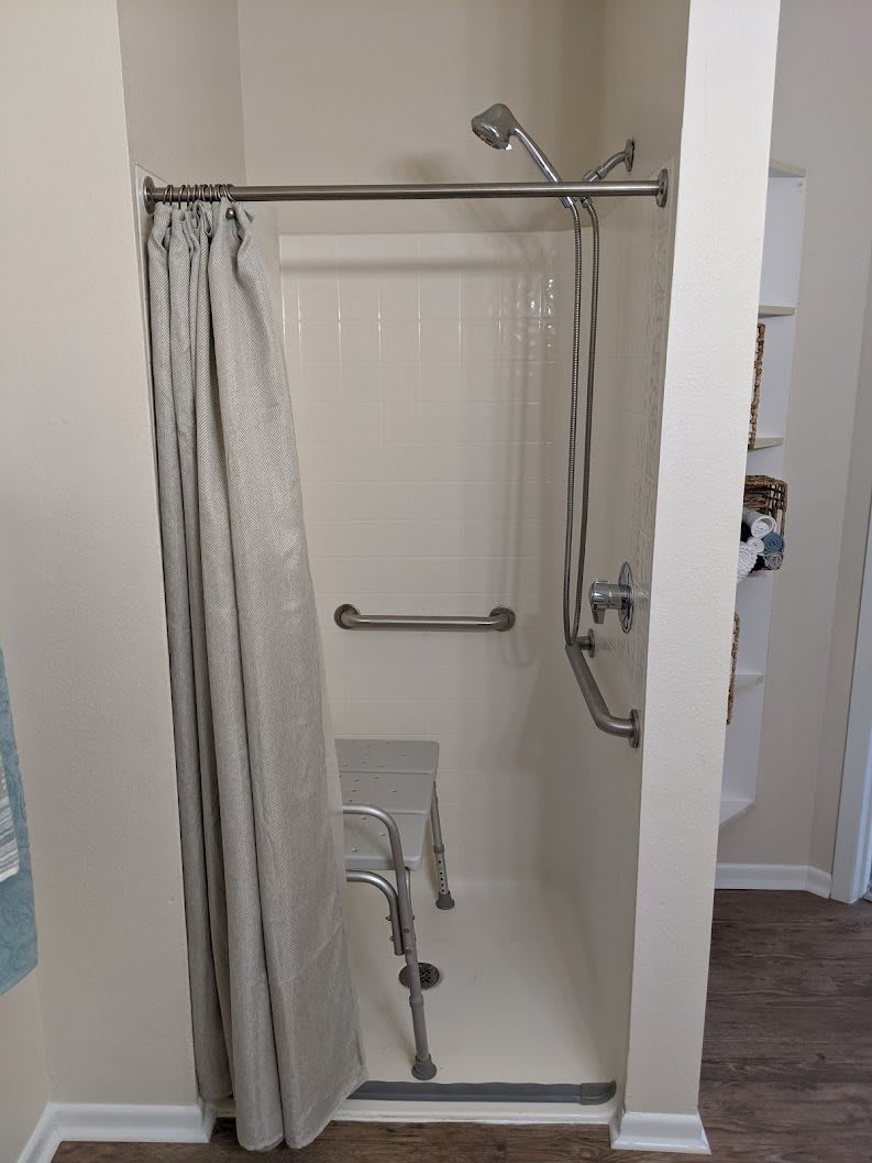 An accessible bathroom shower with a curtain and grab bars.