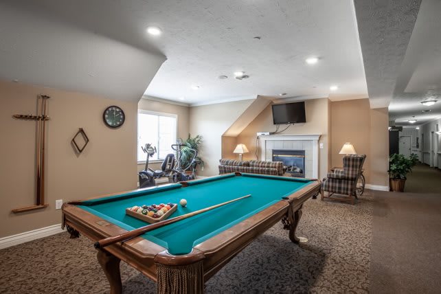 A cozy billiard room featuring a pool table, fireplace, and wall-mounted TV.