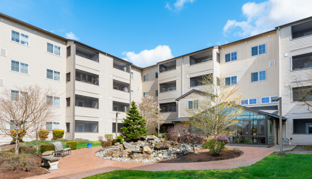 A multi-story residential apartment building with landscaped surroundings on a sunny day.