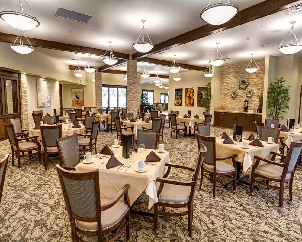 A spacious and elegant dining room with neatly arranged tables and chairs, featuring sophisticated interior design and lighting.