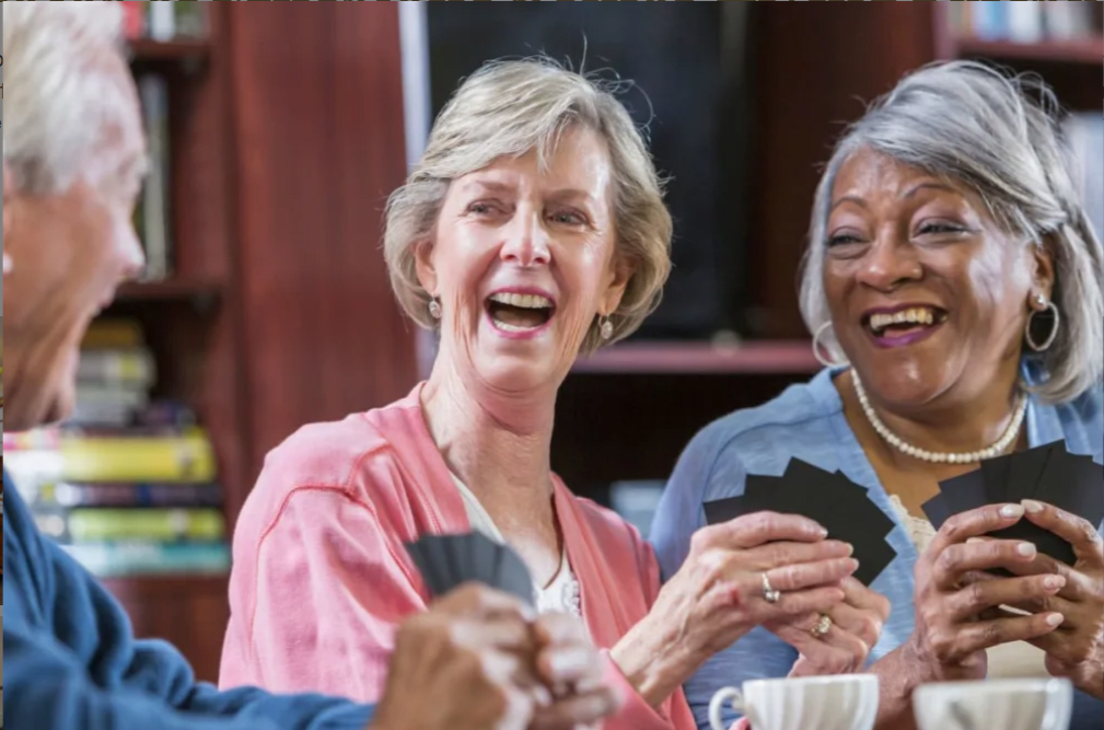 A group of seniors enjoying a card game together, smiling and having fun indoors.