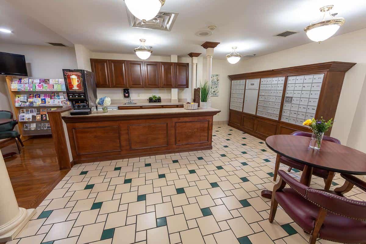 A well-organized lobby area with a reception desk, tiled floor, and mailboxes.