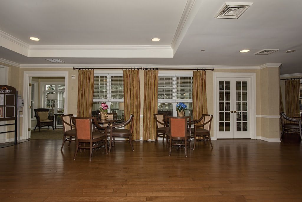 Spacious dining area with hardwood flooring and elegant curtains.