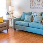 A cozy living room with a blue sofa, armchair, and stylish decor.