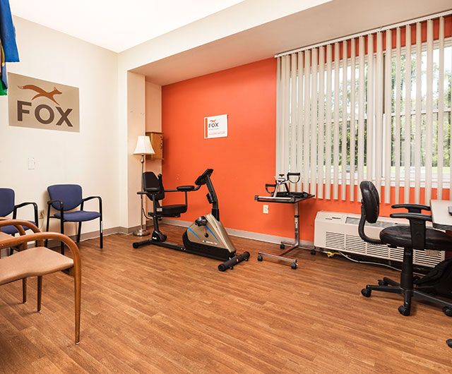 A small office space with an exercise bike, chairs, and wooden flooring.
