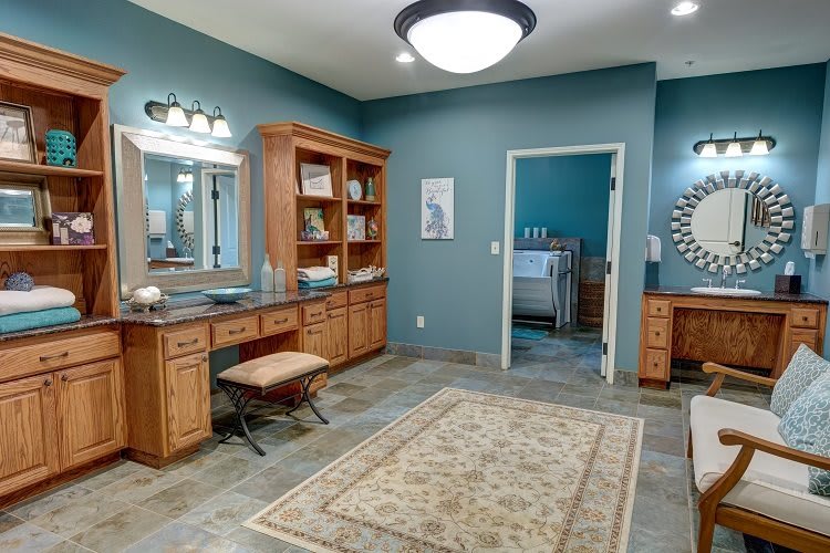 A spacious bathroom featuring a wooden vanity, mirror, and a decorative rug against blue walls.