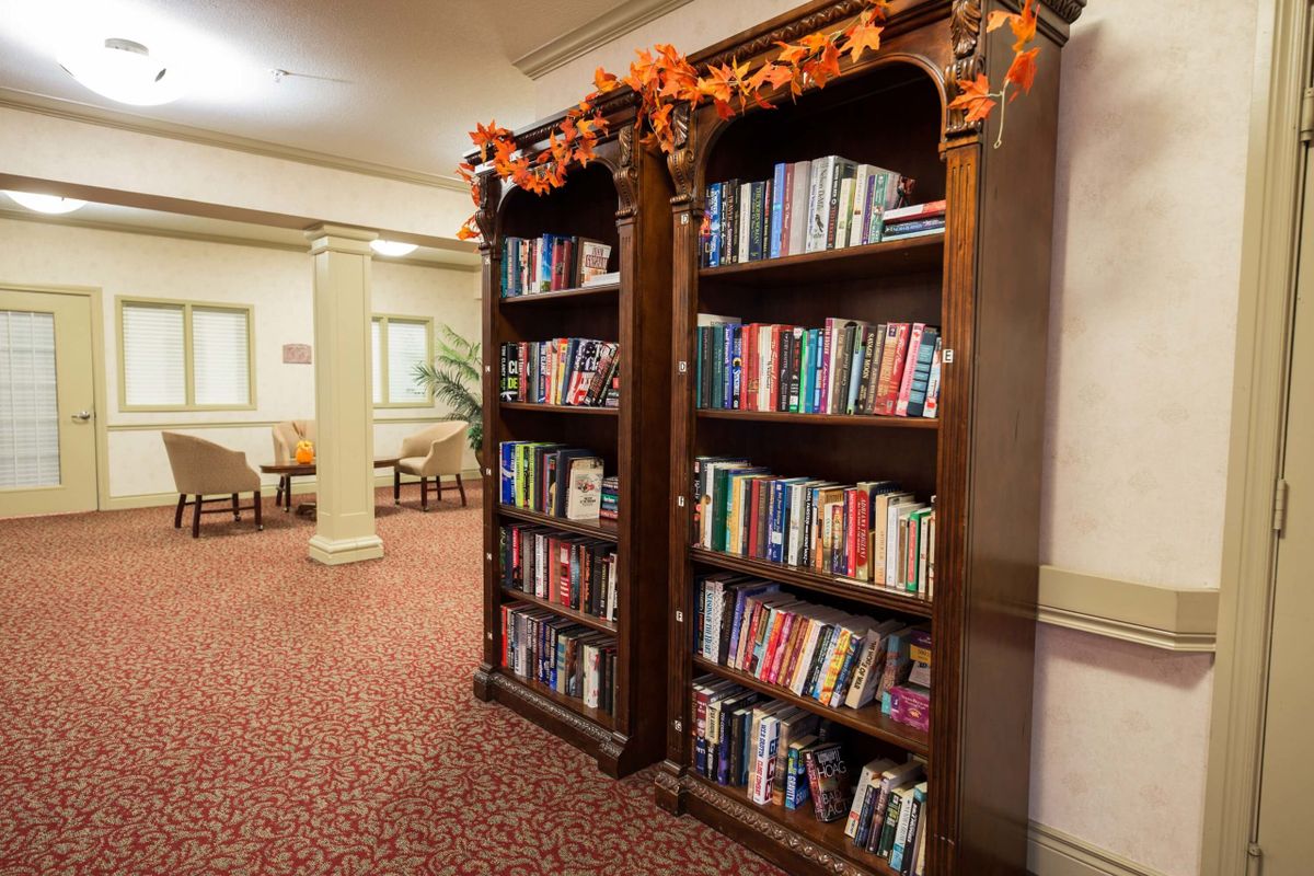 A cozy library corner with bookshelves adorned with autumn decorations.