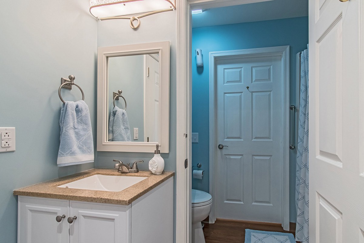 A modern bathroom with a sink, mirror, and blue walls.