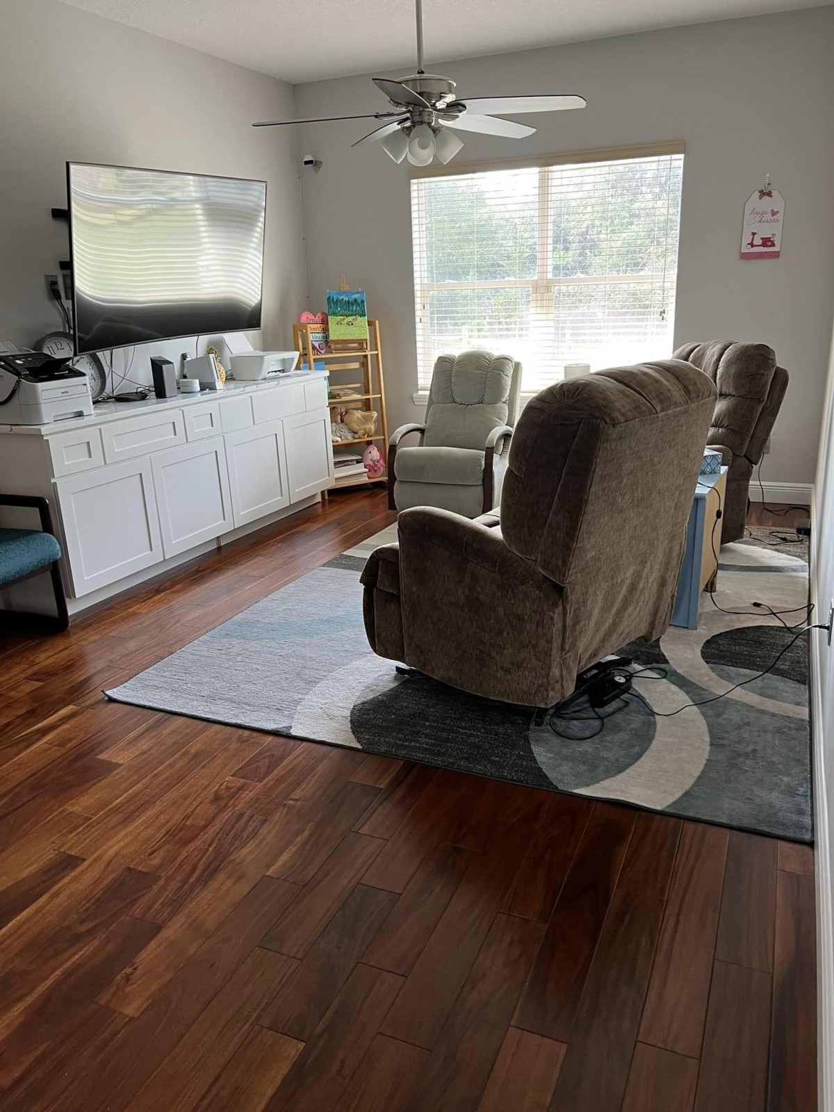 Cozy living room with chairs, a TV, and a large window.