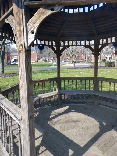 A peaceful gazebo surrounded by green grass, perfect for relaxation in the park.
