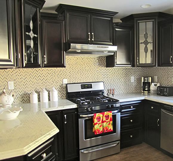A modern kitchen with dark cabinets and stainless steel appliances.