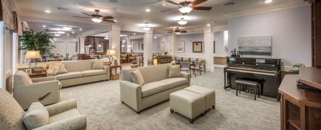 A comfortable and modern lounge area with sofas, tables, and overhead ceiling fans.