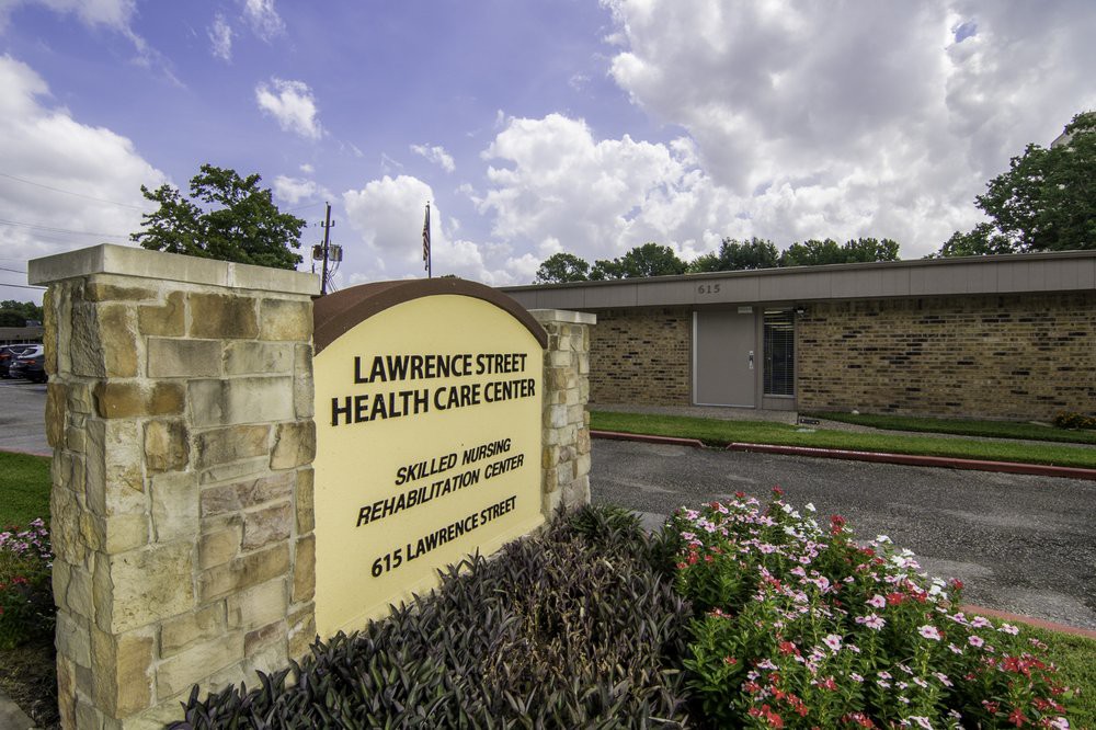 Entrance to a healthcare center with a sign and surrounding greenery.