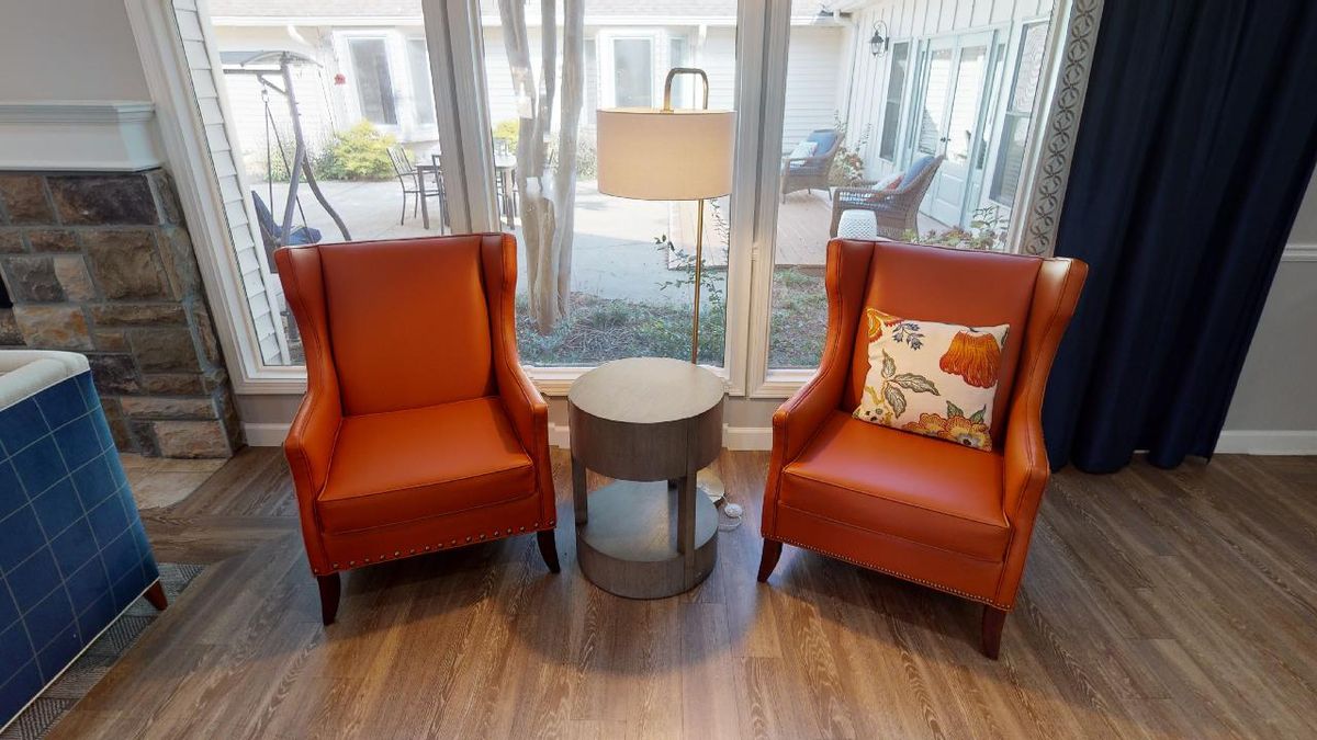 Two orange chairs with a side table and lamp in a cozy living area.