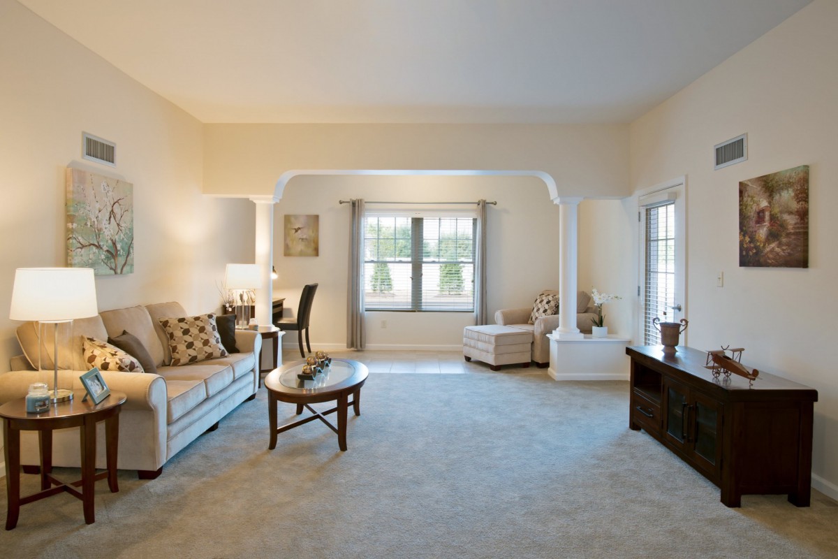 A spacious and elegantly designed living room with modern decor, featuring a comfortable sofa, a round coffee table, and large windows allowing natural light to fill the space.