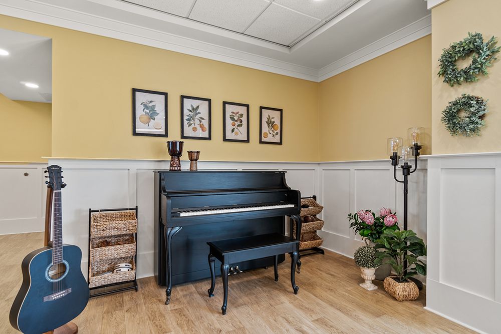 A cozy living room featuring an upright piano, wall art, and decorative elements including plants and candlesticks.