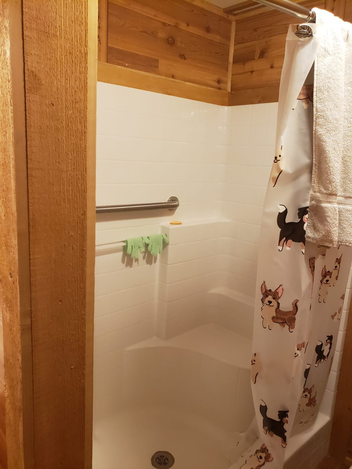 A cozy bathroom with a shower area featuring wood paneling and a decorative curtain.