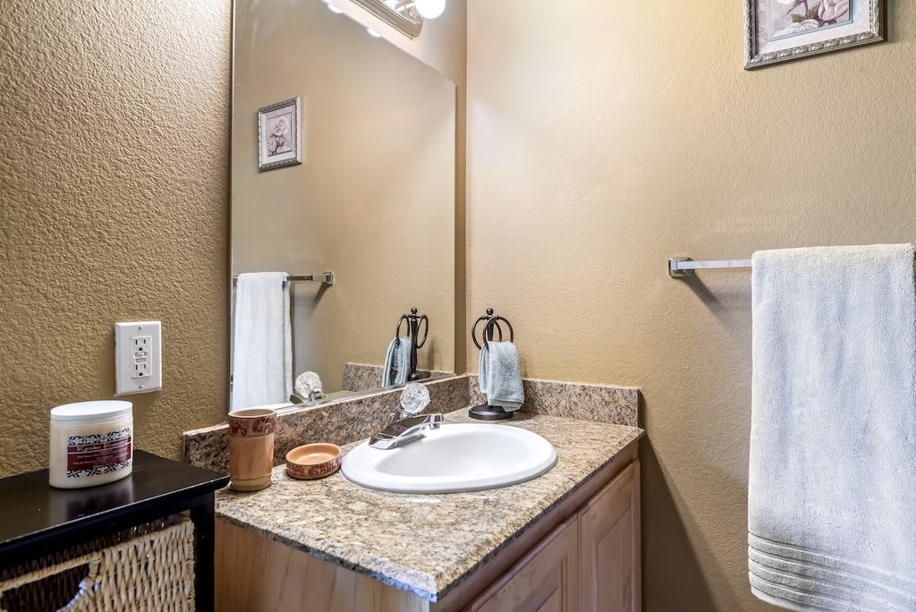 A modern bathroom with a granite countertop and a single sink.