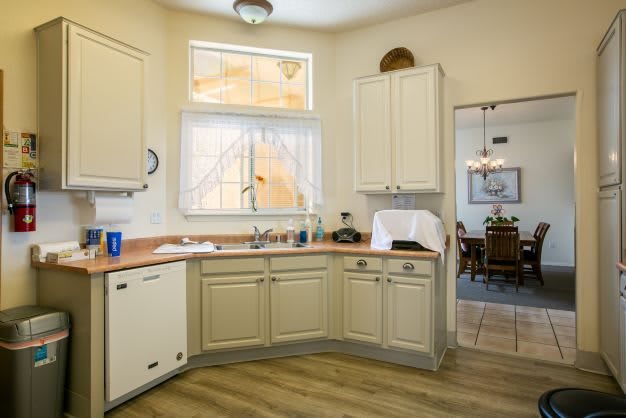 A cozy kitchen with cream-colored cabinets and a view into the dining room.