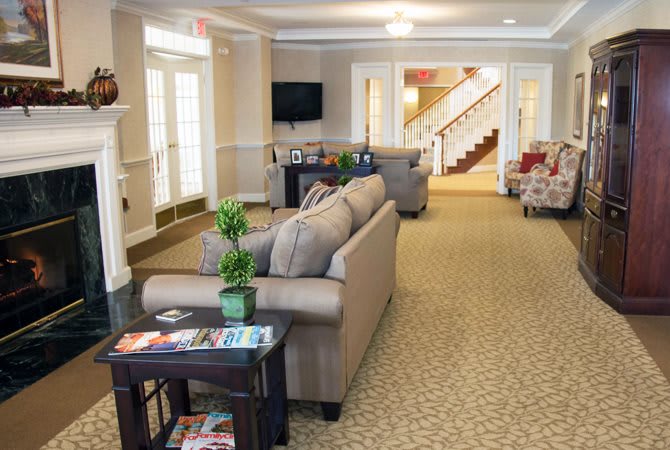A cozy living room with sofas, a television, and a staircase in the background.