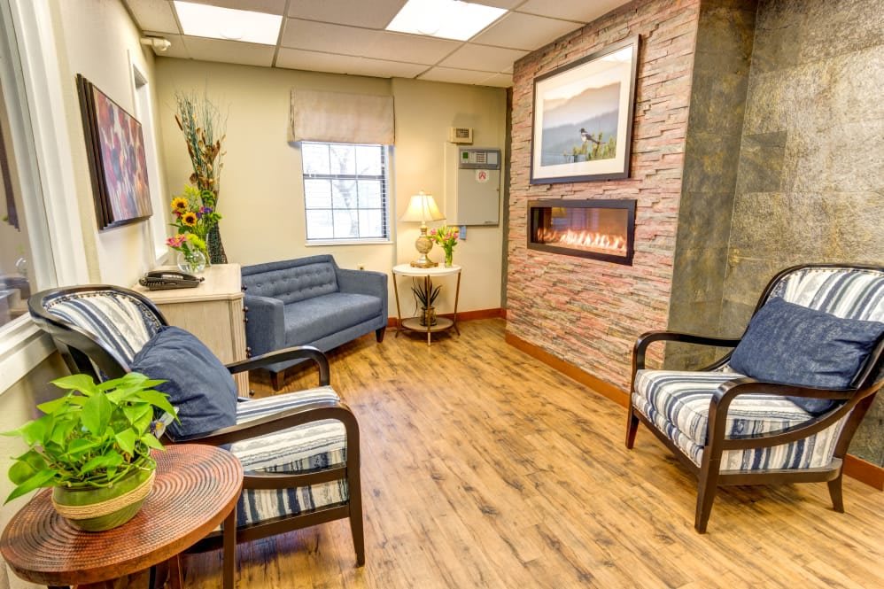 A cozy waiting room with comfortable seating and a warm fireplace.