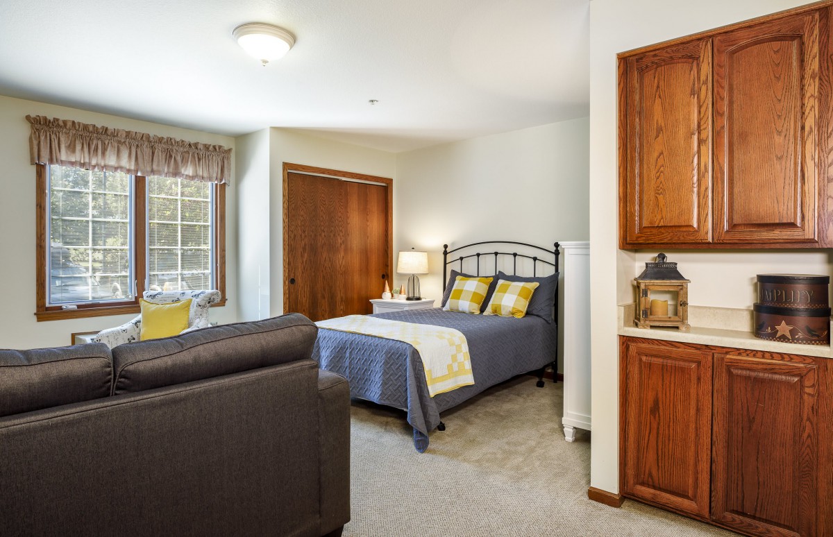 A cozy bedroom with a bed, sofa, and wooden cabinets, creating a warm and inviting atmosphere.