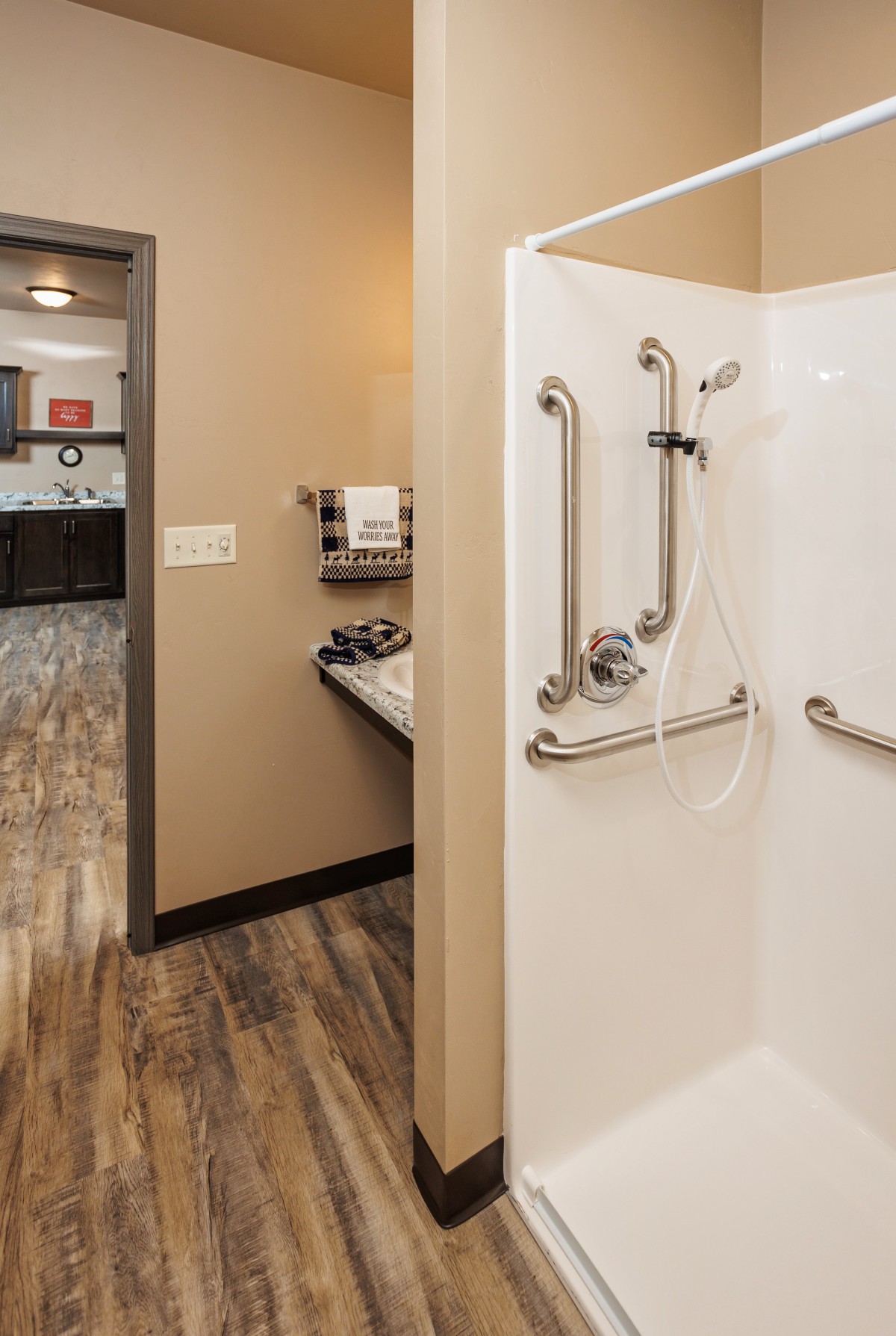 A modern, accessible hotel bathroom with a walk-in shower and grab bars.