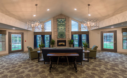 A spacious and modern lobby featuring comfortable seating, a fireplace, and elegant chandeliers.
