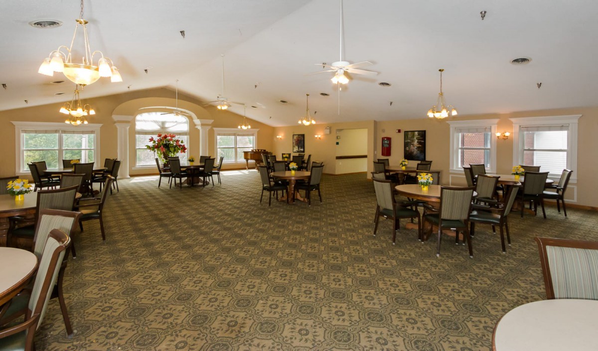 A spacious lobby area with tables and chairs, featuring large windows and decorative lighting.