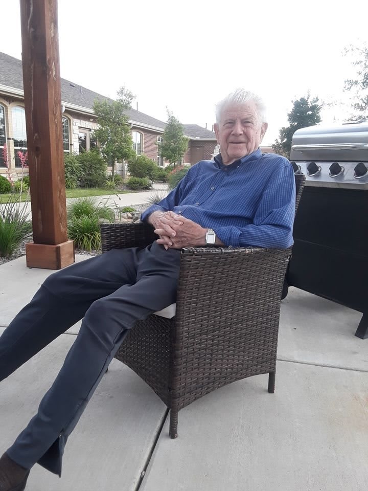An elderly man is relaxing on a patio chair outdoors.