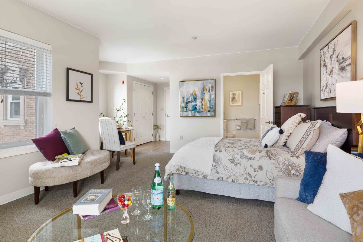 A beautifully decorated bedroom featuring modern decor with a floral bedspread, stylish furniture, and artistic wall hangings.