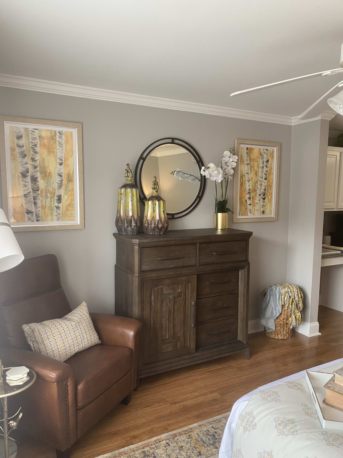 A cozy living room with elegant decor, featuring a dark wooden cabinet topped with decorative items and framed artwork on the walls.