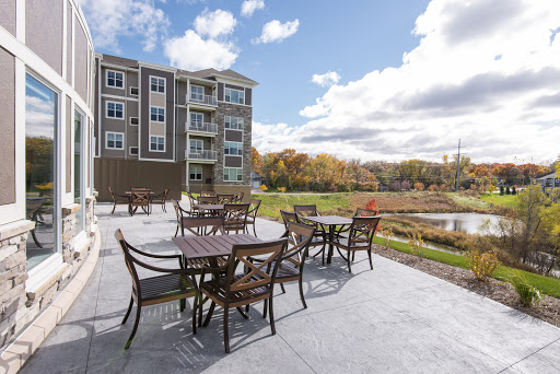 A serene outdoor patio area with tables and chairs, set against a beautiful backdrop of autumn foliage and a clear sky.