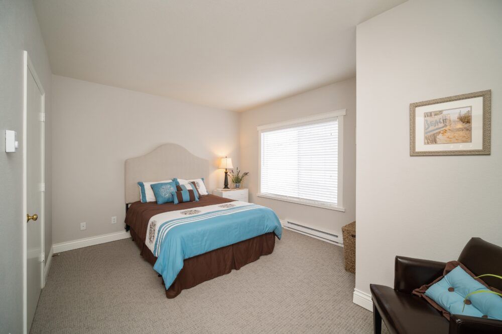 A neatly arranged bedroom with a bed, lamp, and window.