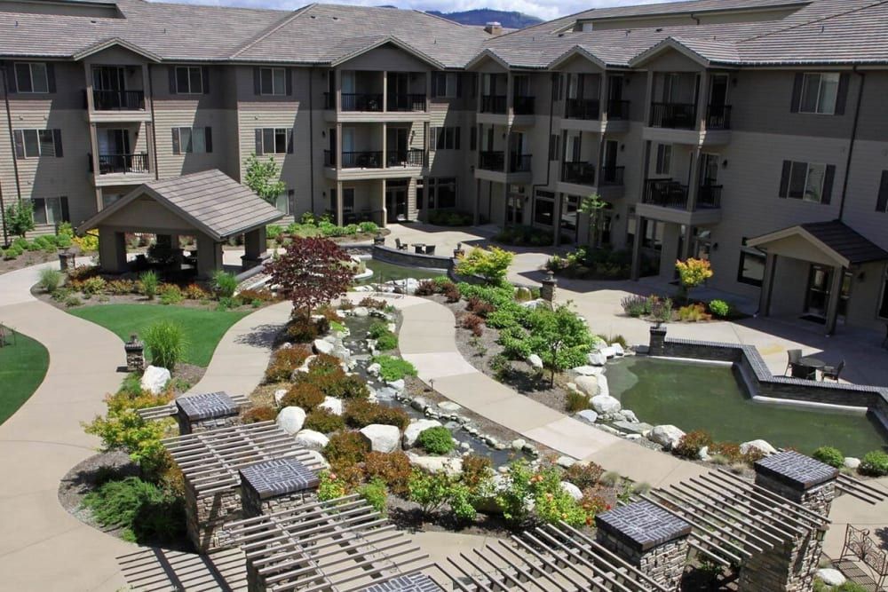 A beautifully landscaped courtyard with a variety of plants and walkways in an apartment complex.