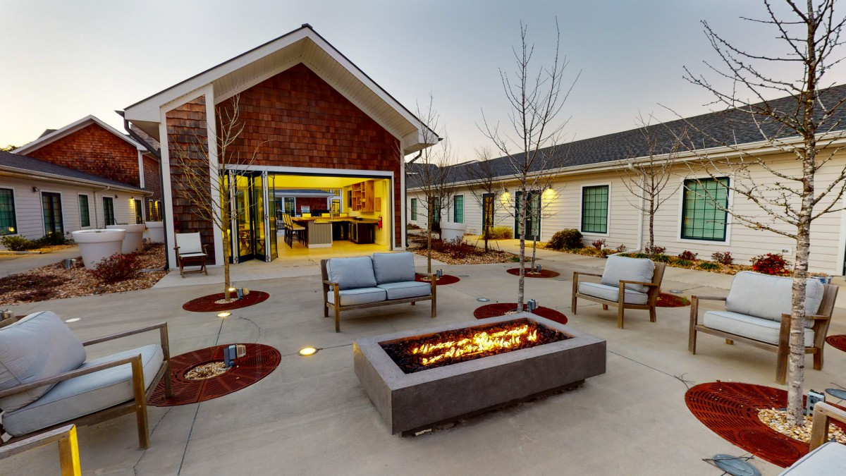 A modern patio with comfortable seating and a fire pit, surrounded by contemporary architecture.