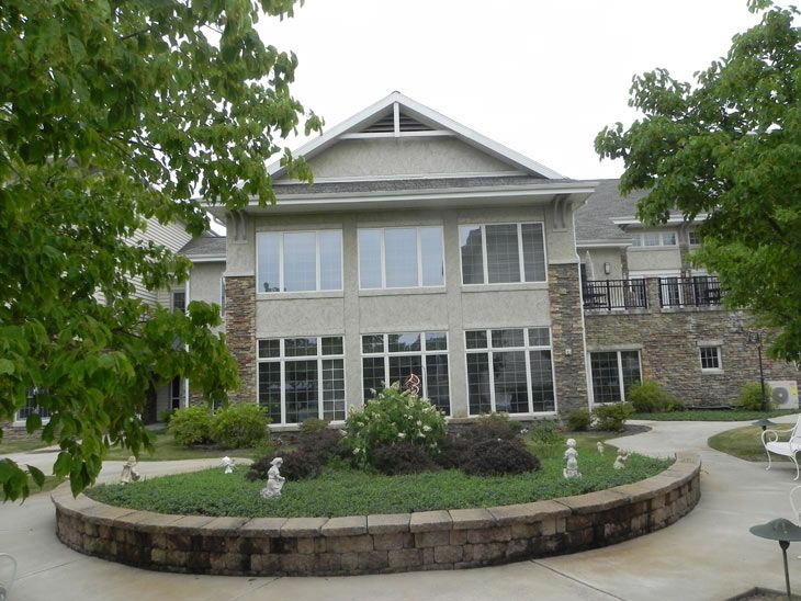 A two-story residential building with large windows and landscaping in front.